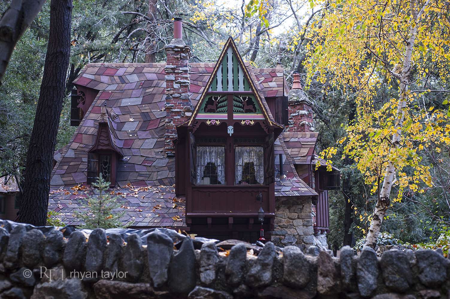 Whimsical cottage with stone wall and autumn trees